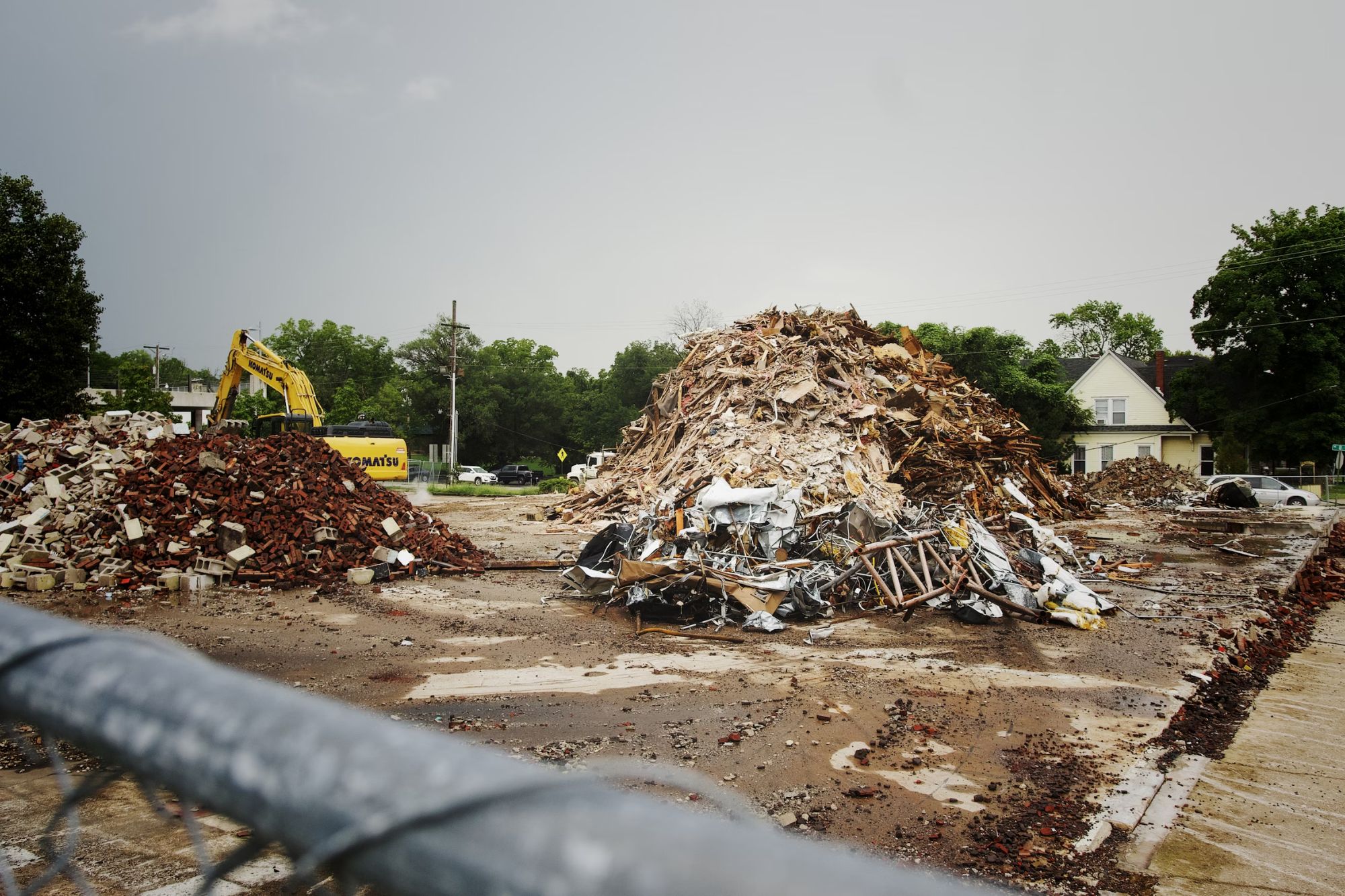 A fence stands behind a pile of rubble, representing demolition work in Austin, TX.