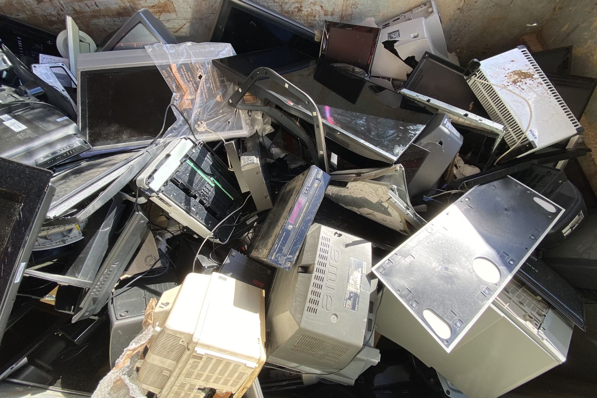 A heap of old electronics in a dumpster, illustrating the e-waste junk removal service offered in Austin, TX.
